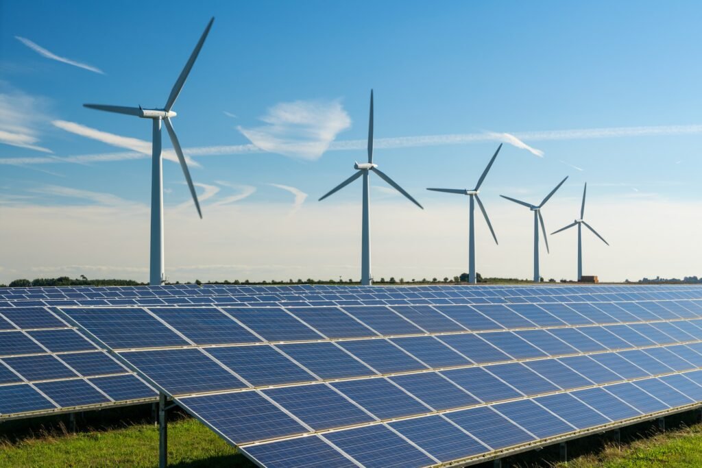 Wind turbines on a wind farm with rows of solar panels underneath in a green field