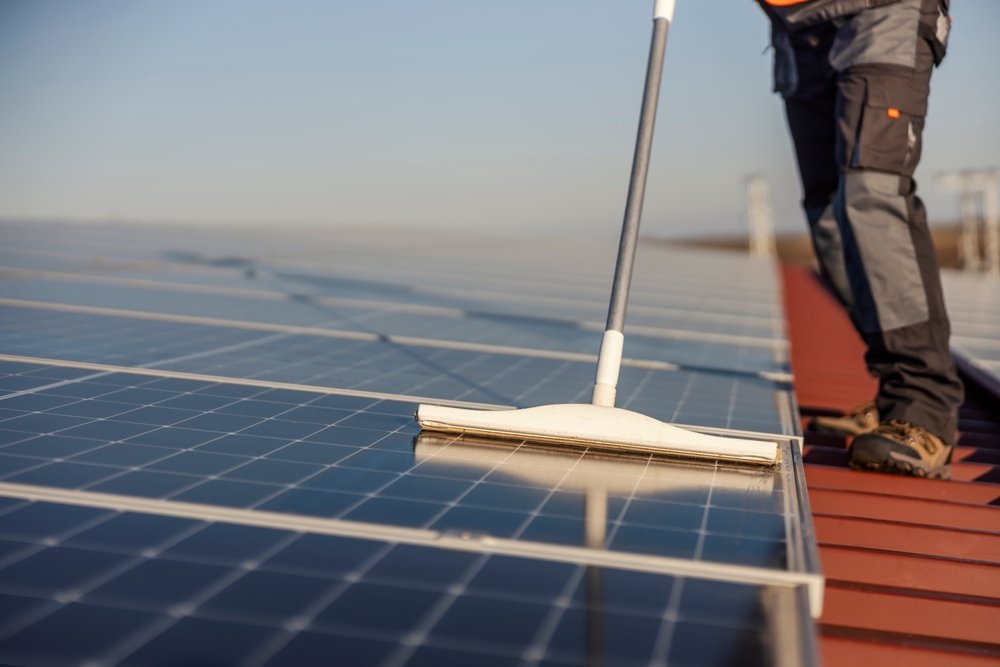 Worker cleaning solar panels on rooftop installation