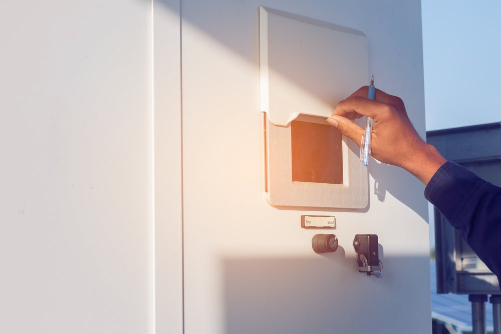 Electrician inspecting solar inverter connections during maintenance